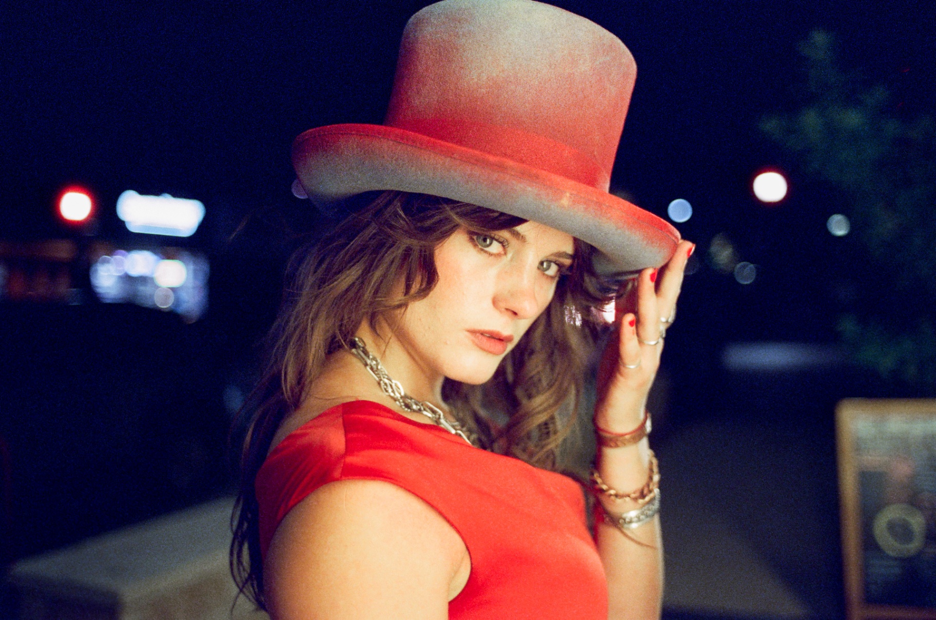 Original 35mm portrait of a woman in a red dress and hat beside a glowing neon sign at night